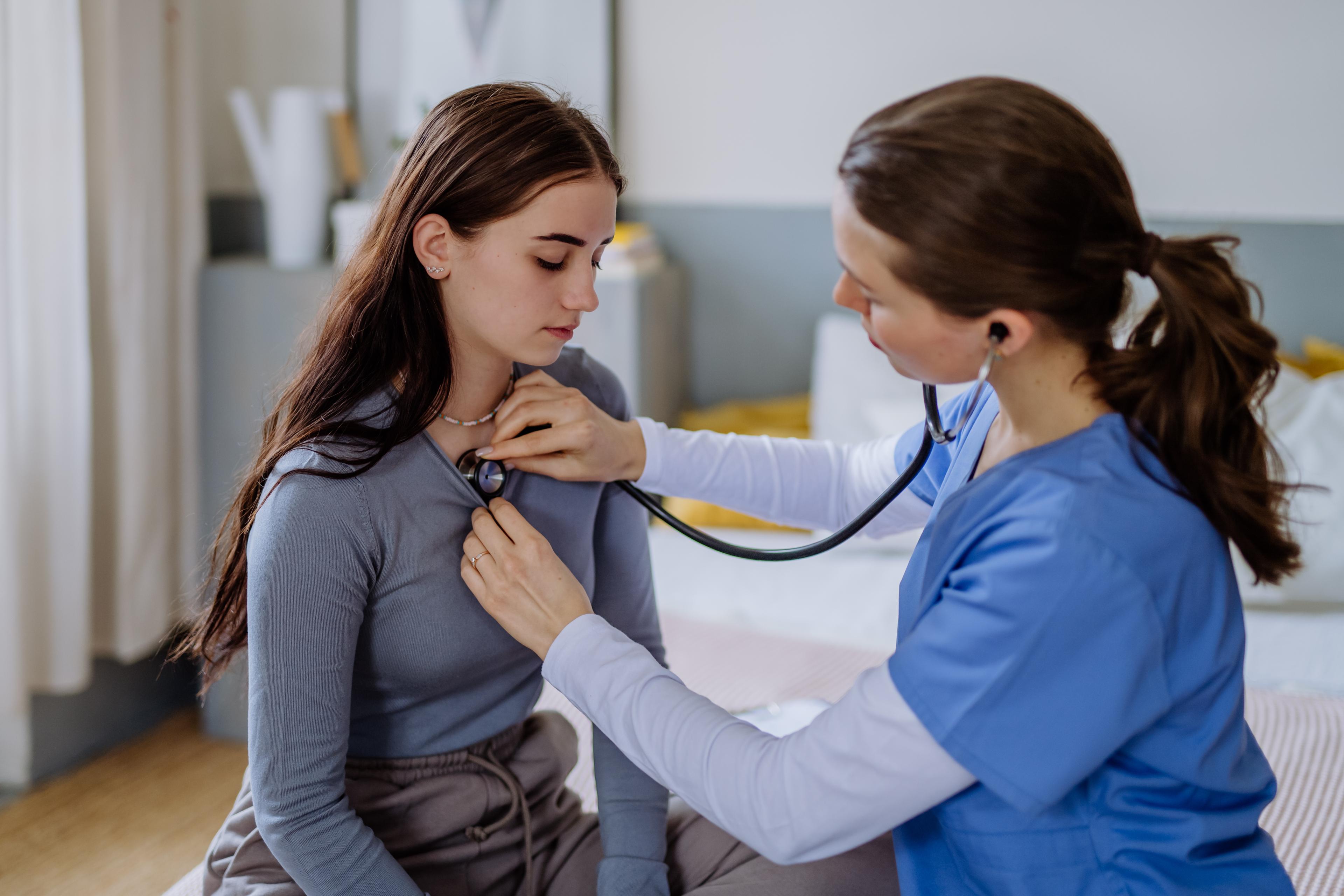 A nurse using a stethoscope on a patient