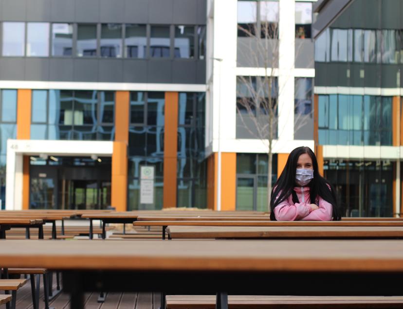 A woman sitting at a bench wearing a mask to prevent COVID