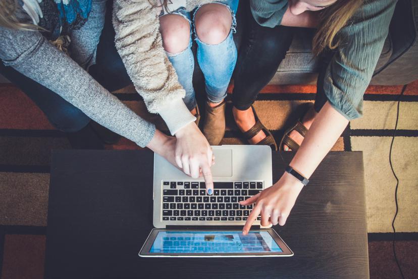 Group of people pointing at laptop screen.