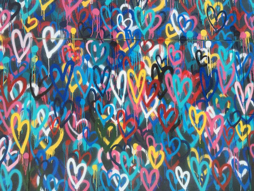 A vibrant and colorful abstract background filled with various heart-shaped graffiti-style designs in a variety of bright, bold colors.