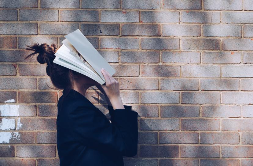 Women covering face with book
