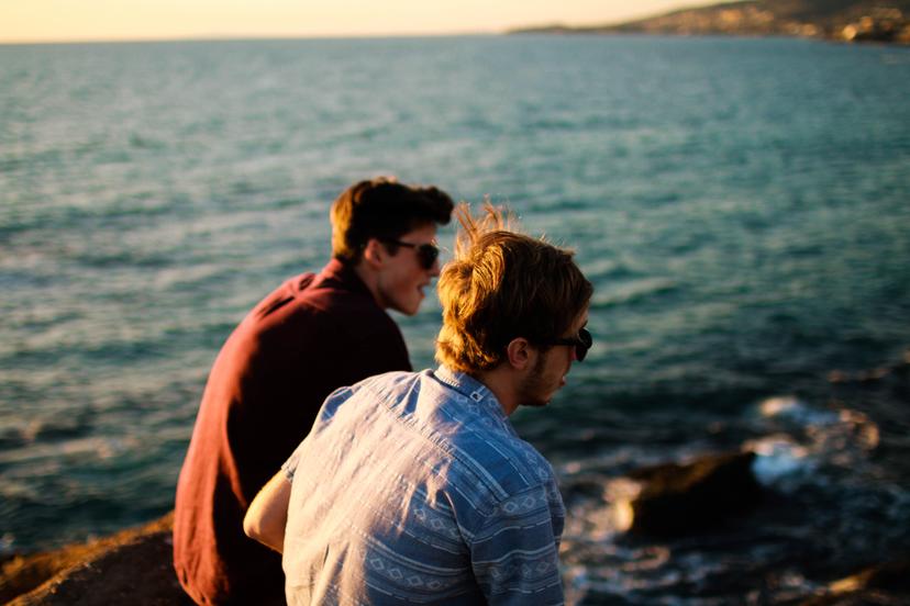 Two young men talking at a beach.