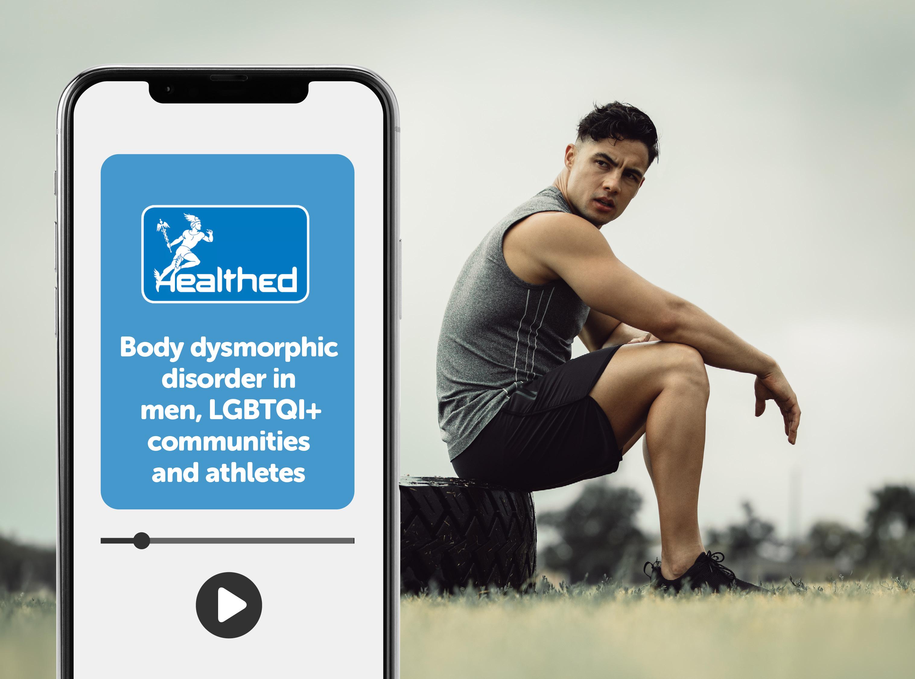 Smartphone displaying a Healthed educational video titled “Body dysmorphic disorder in men, LGBTQI+ communities and athletes.” A video progress bar and play button appear on the phone screen. In the background, a person in athletic clothing sits outdoors on a large tyre in a grassy field.