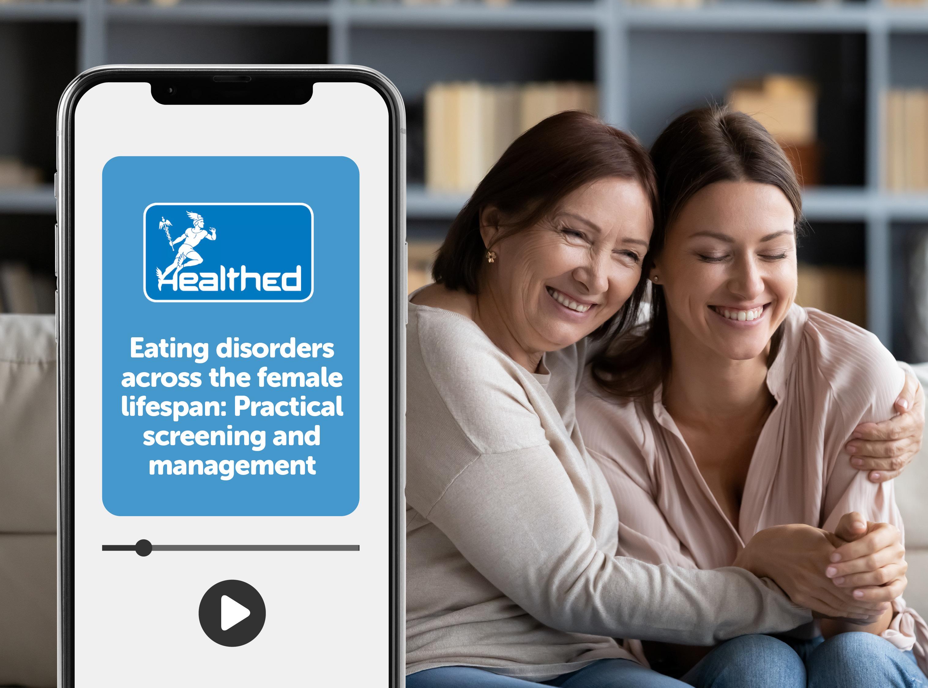 Smartphone displaying a Healthed educational video titled “Eating disorders across the female lifespan: Practical screening and management.” A video progress bar and play button appear on the phone screen. In the background, two adults sit together on a sofa in front of bookshelves, with one person embracing the other.